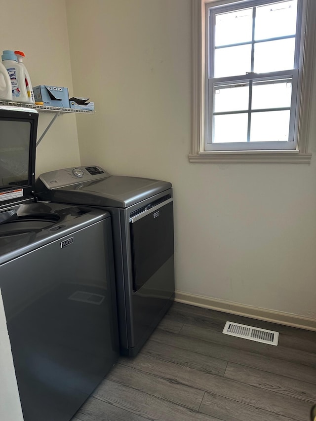 clothes washing area featuring separate washer and dryer and hardwood / wood-style flooring