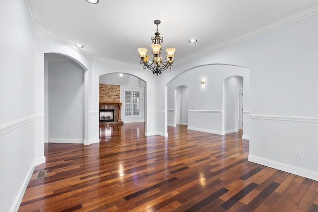 interior space featuring a large fireplace, ornamental molding, dark hardwood / wood-style floors, and a notable chandelier