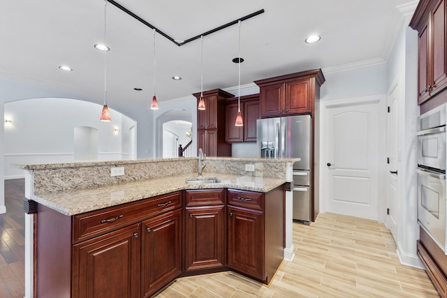 kitchen with sink, pendant lighting, appliances with stainless steel finishes, and an island with sink