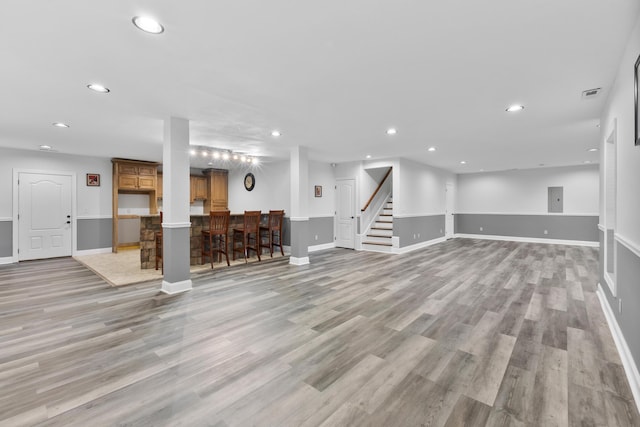 unfurnished living room with bar area and light hardwood / wood-style flooring