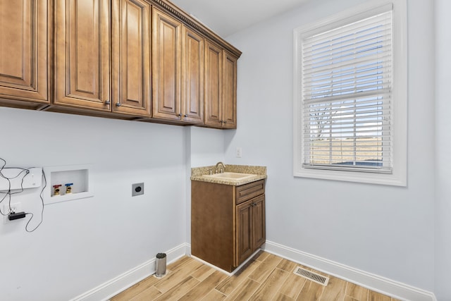 laundry room with sink, hookup for a washing machine, light wood-type flooring, electric dryer hookup, and cabinets