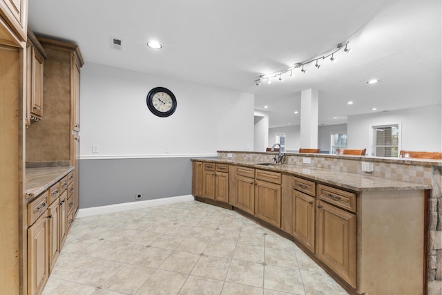 kitchen with light tile patterned floors, light stone countertops, and sink