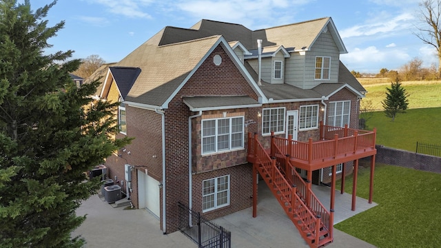 exterior space featuring a lawn, a garage, central AC, a wooden deck, and a patio