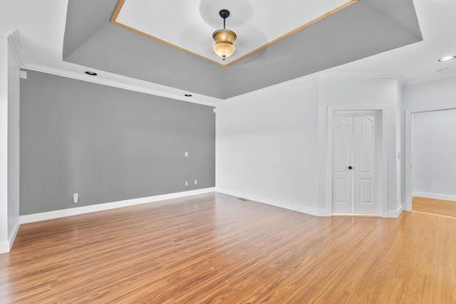 unfurnished room with light hardwood / wood-style floors, a tray ceiling, and ornamental molding