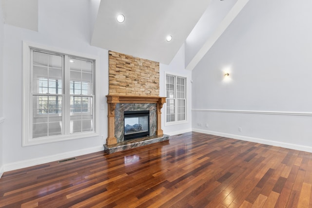 unfurnished living room with high vaulted ceiling, hardwood / wood-style floors, and a premium fireplace