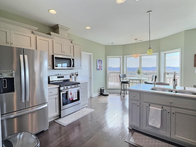 kitchen with light countertops, backsplash, a sink, stainless steel appliances, and dark wood-style flooring