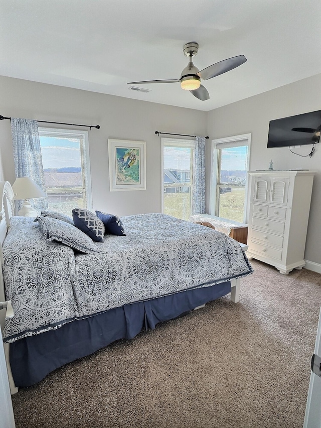 carpeted bedroom with visible vents, baseboards, and ceiling fan