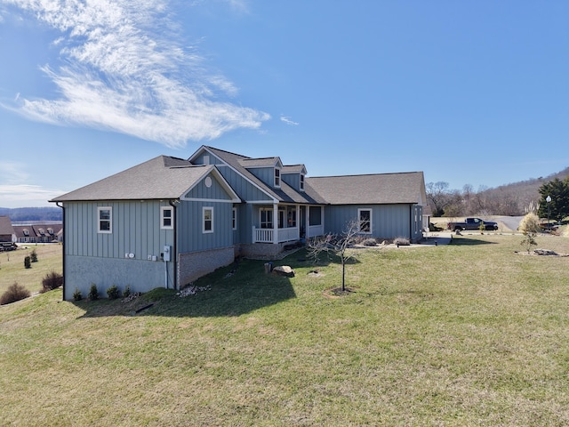 view of front facade featuring board and batten siding, a front yard, and roof with shingles