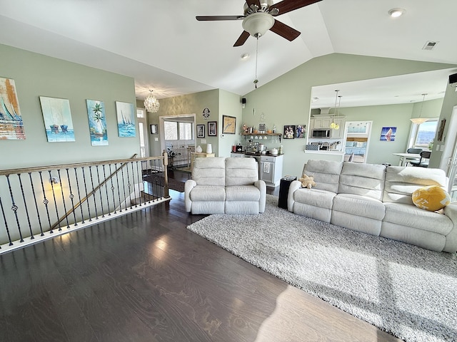living room with a wealth of natural light, ceiling fan with notable chandelier, vaulted ceiling, and wood finished floors