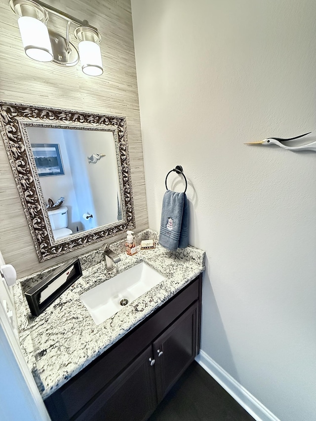 bathroom with baseboards, toilet, and vanity