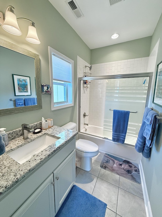 bathroom featuring tile patterned floors, toilet, vanity, visible vents, and shower / bath combination with glass door