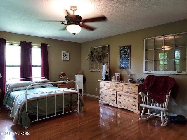 bedroom with ceiling fan, dark hardwood / wood-style flooring, and a textured ceiling