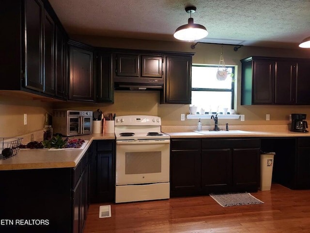 kitchen with white electric range, sink, a textured ceiling, decorative light fixtures, and light hardwood / wood-style floors