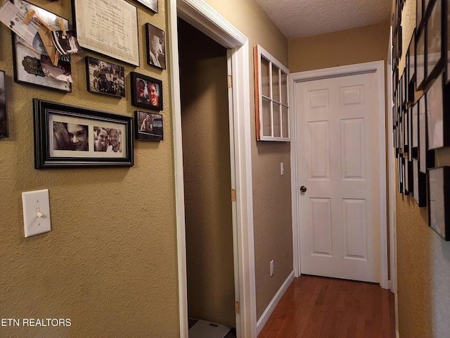 hall with a textured ceiling and hardwood / wood-style flooring