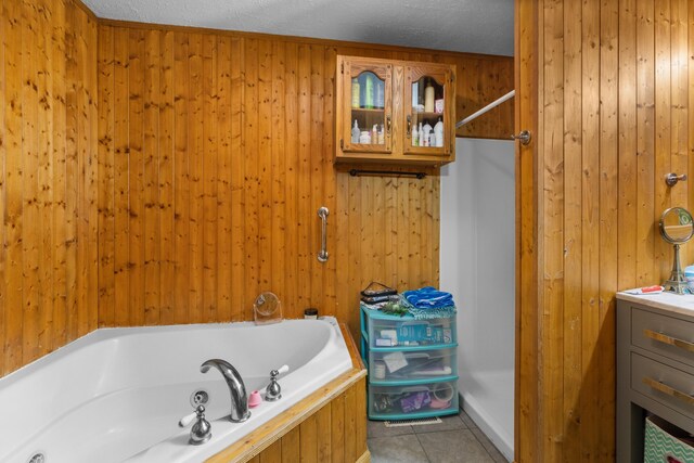 full bath featuring a tub to relax in, wooden walls, a textured ceiling, and tile patterned floors