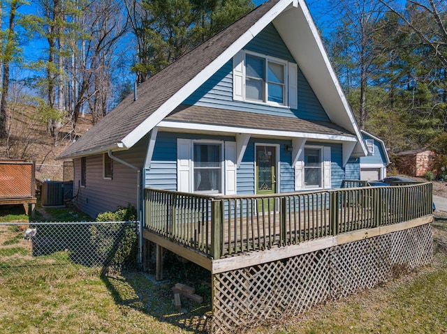 rear view of house featuring central air condition unit, a shingled roof, fence, and a yard