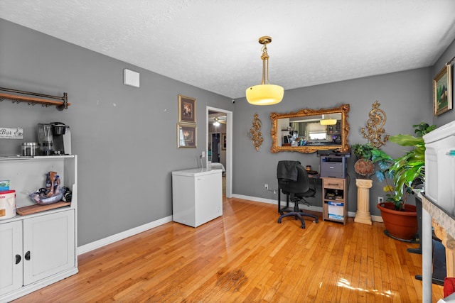 office area with baseboards, a textured ceiling, and light wood finished floors