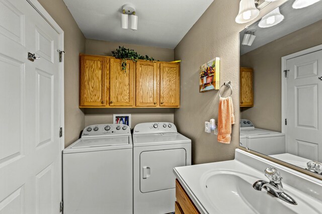 clothes washing area featuring cabinets, washing machine and dryer, and sink