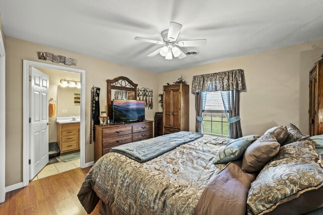 bedroom featuring ensuite bathroom, light hardwood / wood-style flooring, and ceiling fan