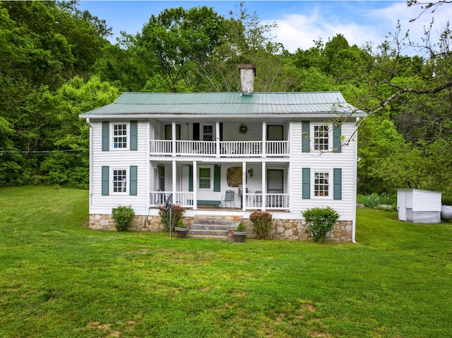 view of front of property featuring covered porch, a balcony, a chimney, and metal roof