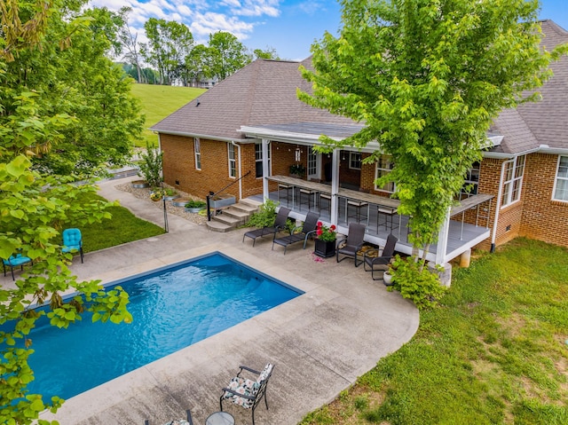 outdoor pool with a patio area, an outdoor bar, and a lawn