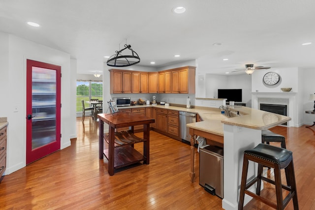 kitchen with a breakfast bar, ceiling fan, a peninsula, light countertops, and appliances with stainless steel finishes