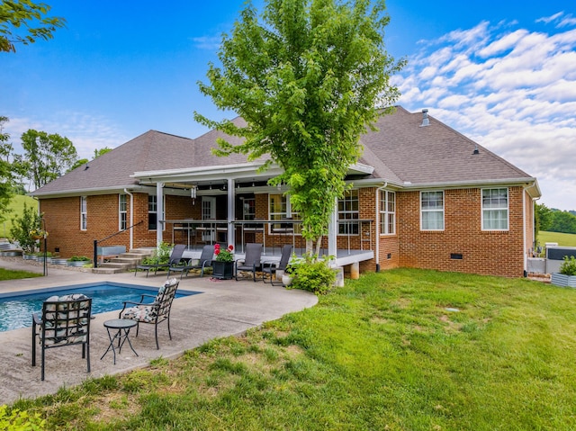 back of house with brick siding, an outdoor pool, a yard, a patio, and entry steps