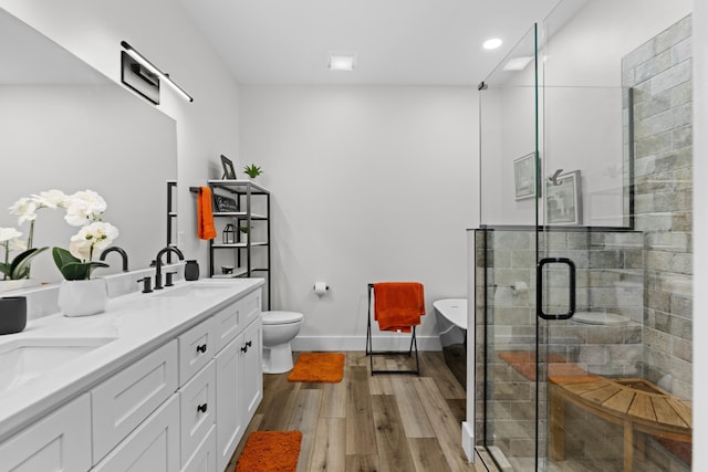 full bathroom with toilet, wood-type flooring, vanity, and separate shower and tub