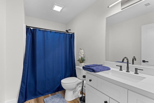 bathroom featuring wood-type flooring, vanity, toilet, and walk in shower