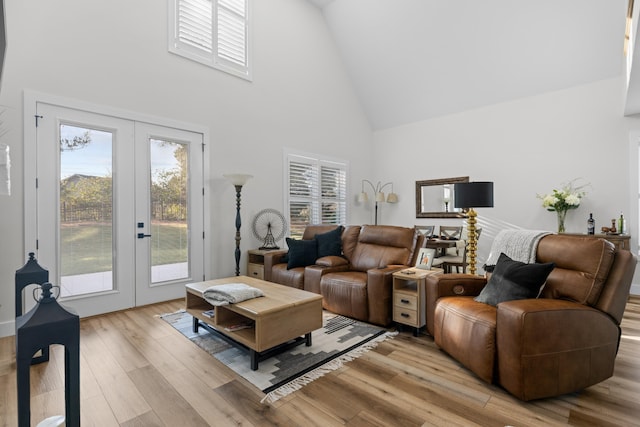 living room featuring french doors, light wood-type flooring, and high vaulted ceiling