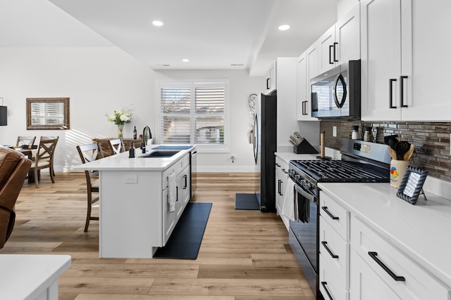 kitchen featuring a kitchen island with sink, a kitchen breakfast bar, sink, white cabinetry, and stainless steel appliances