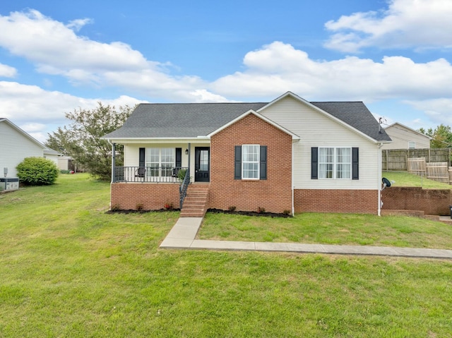 view of front of house featuring covered porch, fence, a front yard, brick siding, and roof with shingles