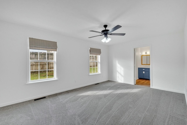 empty room with ceiling fan, baseboards, carpet flooring, and visible vents