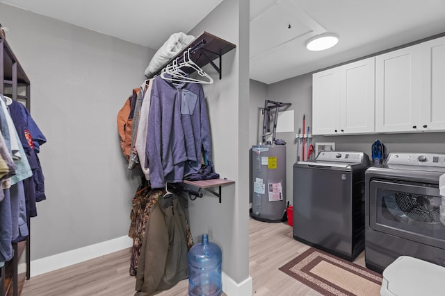 laundry room featuring water heater, washer and clothes dryer, cabinet space, and light wood-style floors