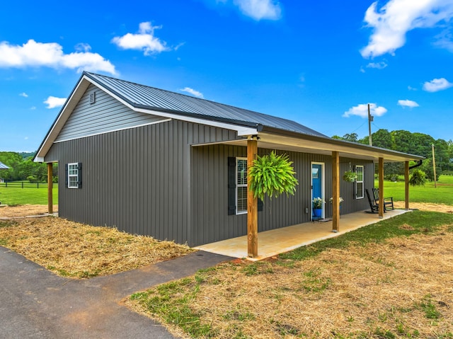 view of side of home with metal roof, a patio, and a yard