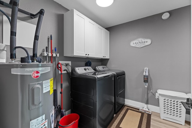laundry area featuring electric water heater, cabinet space, independent washer and dryer, light wood finished floors, and baseboards