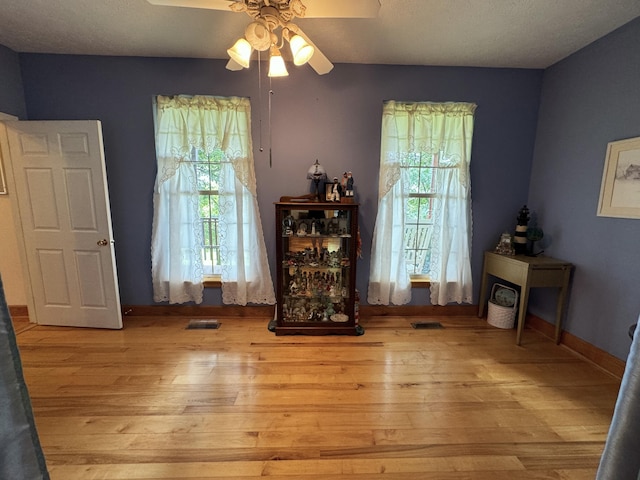 sitting room with light wood-type flooring, plenty of natural light, and ceiling fan