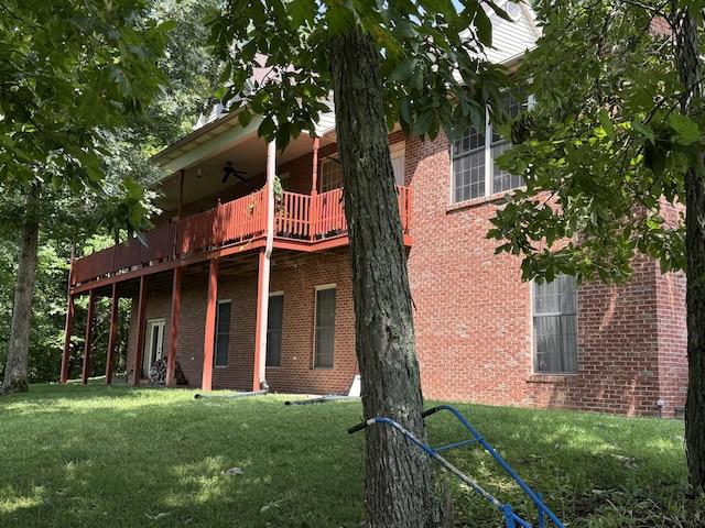 back of property featuring ceiling fan, a balcony, and a yard