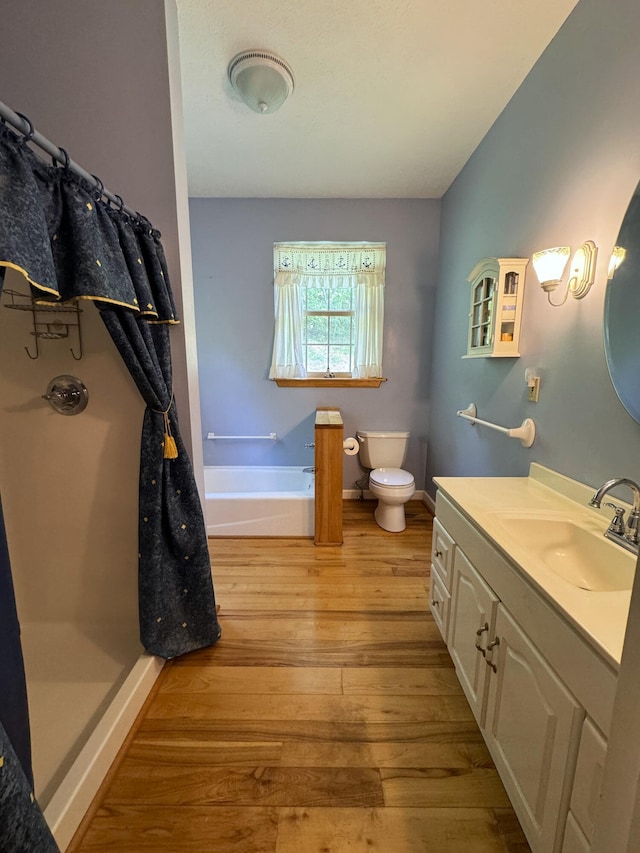 bathroom with a bathtub, hardwood / wood-style floors, vanity, and toilet