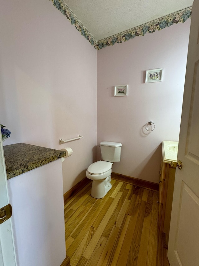 bathroom with hardwood / wood-style flooring, vanity, toilet, and a textured ceiling