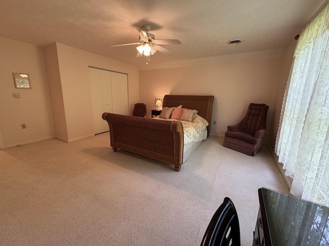 bedroom featuring light carpet, a textured ceiling, a closet, and ceiling fan