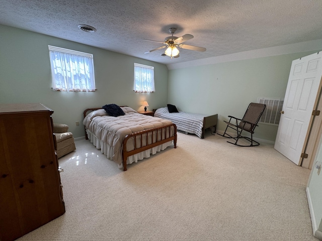 bedroom with ceiling fan, light colored carpet, and a textured ceiling