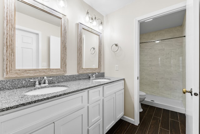 bathroom featuring vanity, toilet, and a tile shower