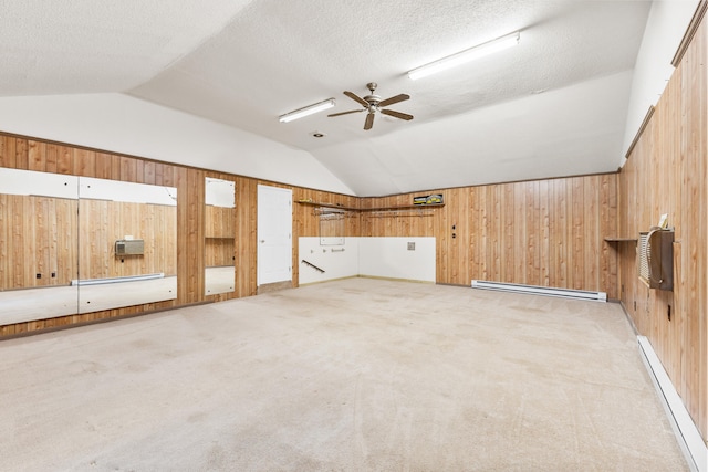 additional living space featuring wood walls, lofted ceiling, carpet, and a baseboard heating unit