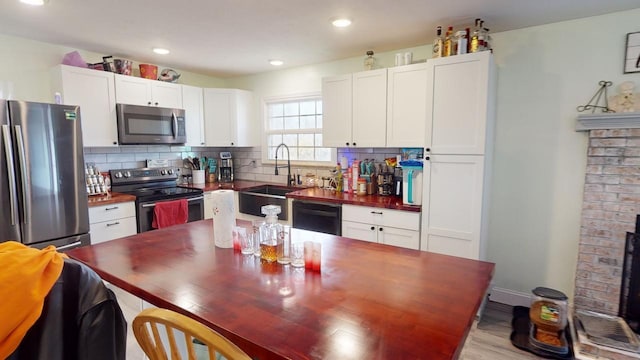 kitchen with sink, backsplash, stainless steel appliances, and white cabinets