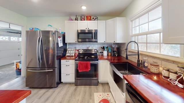 kitchen featuring tasteful backsplash, stainless steel appliances, light hardwood / wood-style floors, and white cabinets