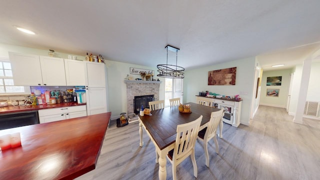 dining area with a stone fireplace and light hardwood / wood-style flooring