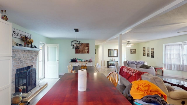 dining area with ceiling fan, hardwood / wood-style floors, and a brick fireplace