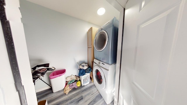 laundry room featuring wood-type flooring and stacked washing maching and dryer