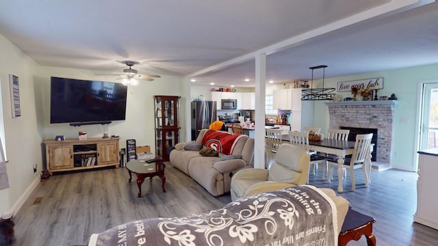 living room featuring wood-type flooring, ceiling fan, and a fireplace